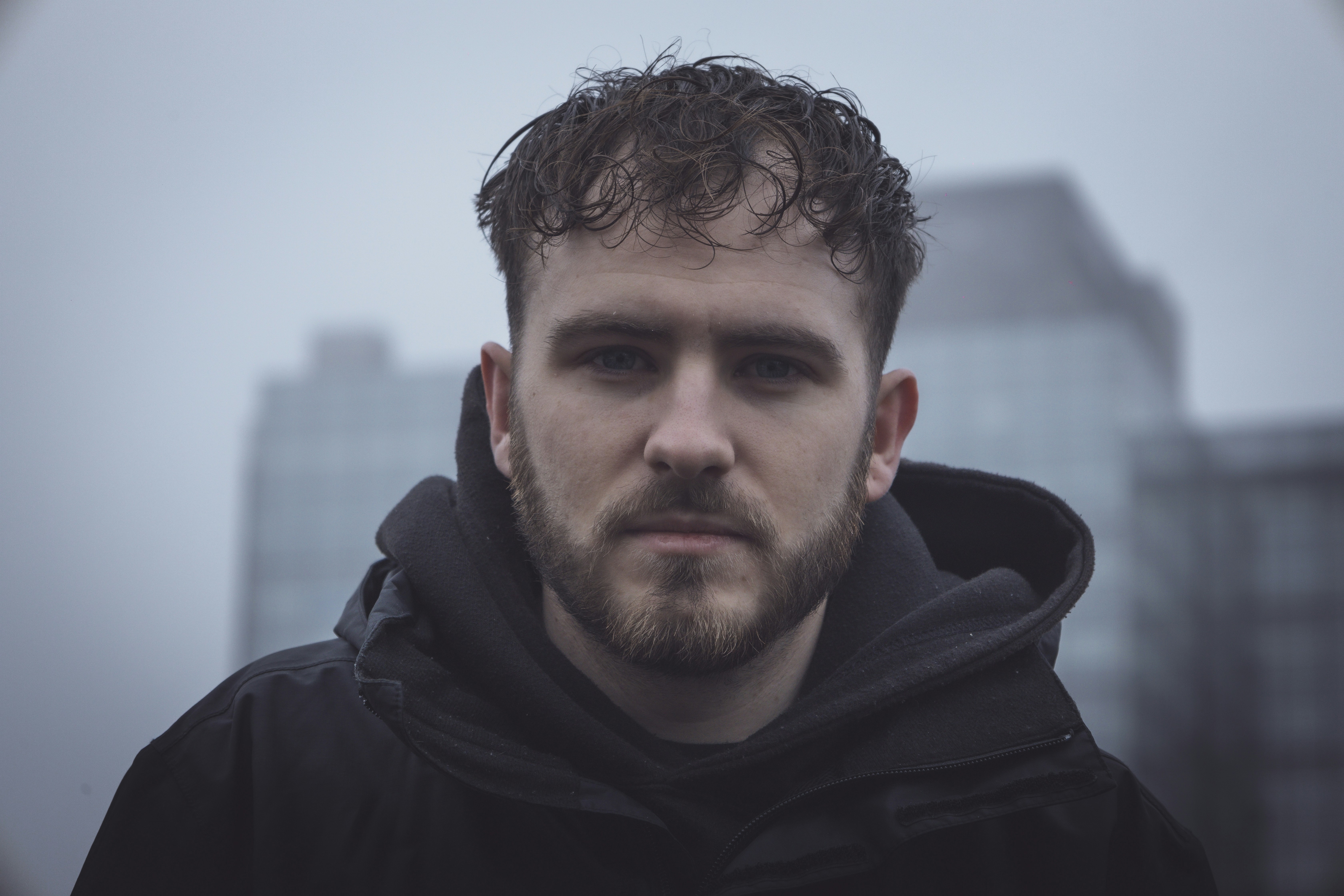a man with a beard standing in front of a tall building
