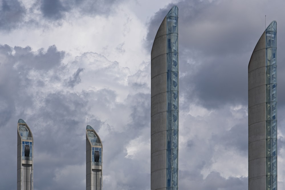 a couple of tall towers sitting under a cloudy sky