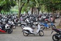 a large group of motor scooters parked on the side of a road