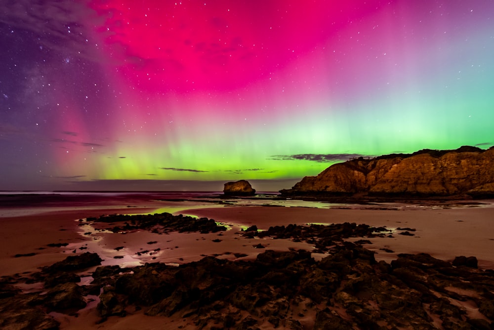 una aurora se cernía sobre una playa rocosa bajo un cielo púrpura
