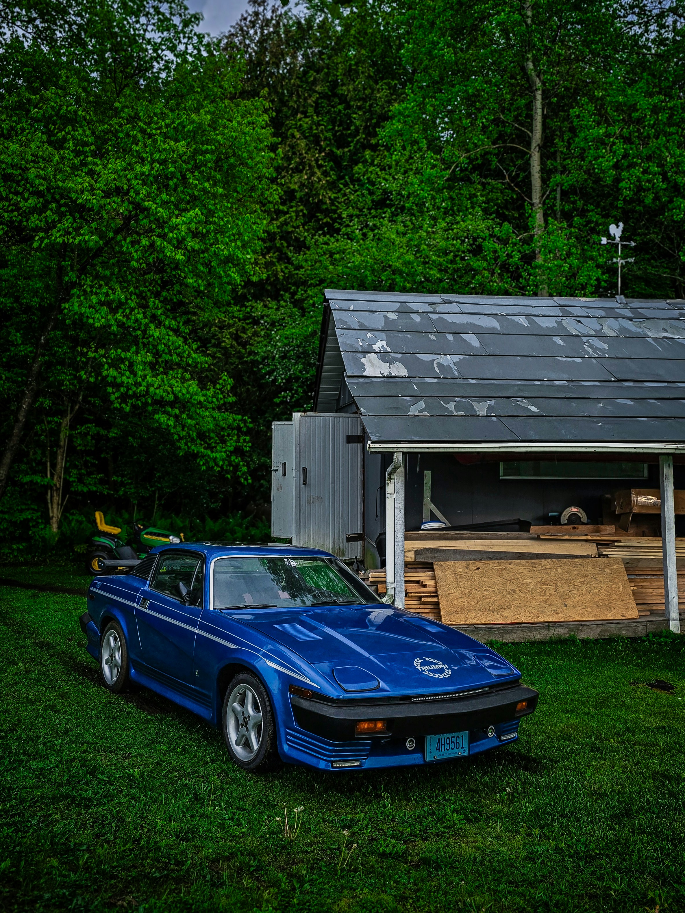 a blue sports car parked in front of a shed