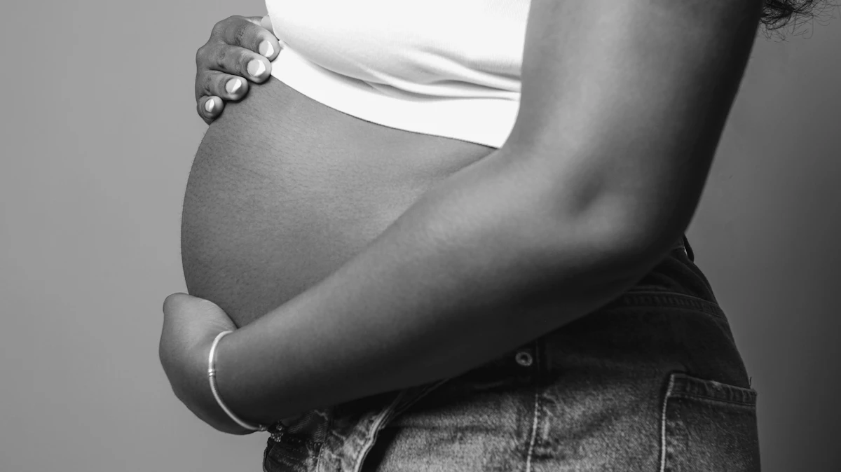 Pregnant woman gently holding her belly, black-and-white photo