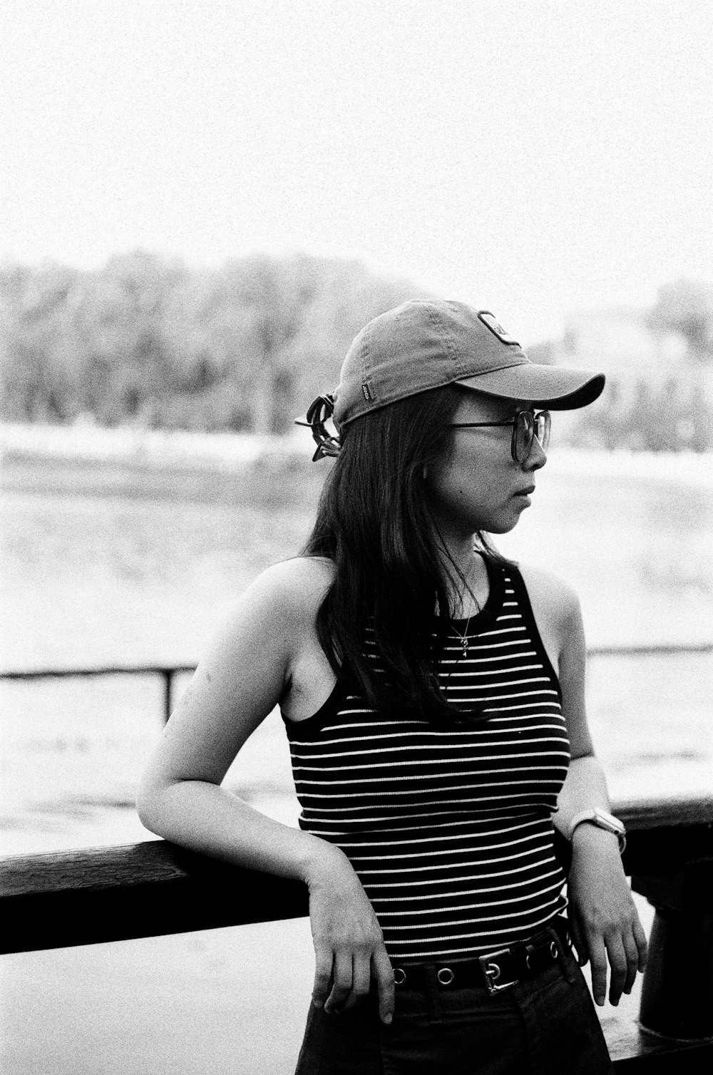 a woman wearing a hat and glasses leaning on a rail