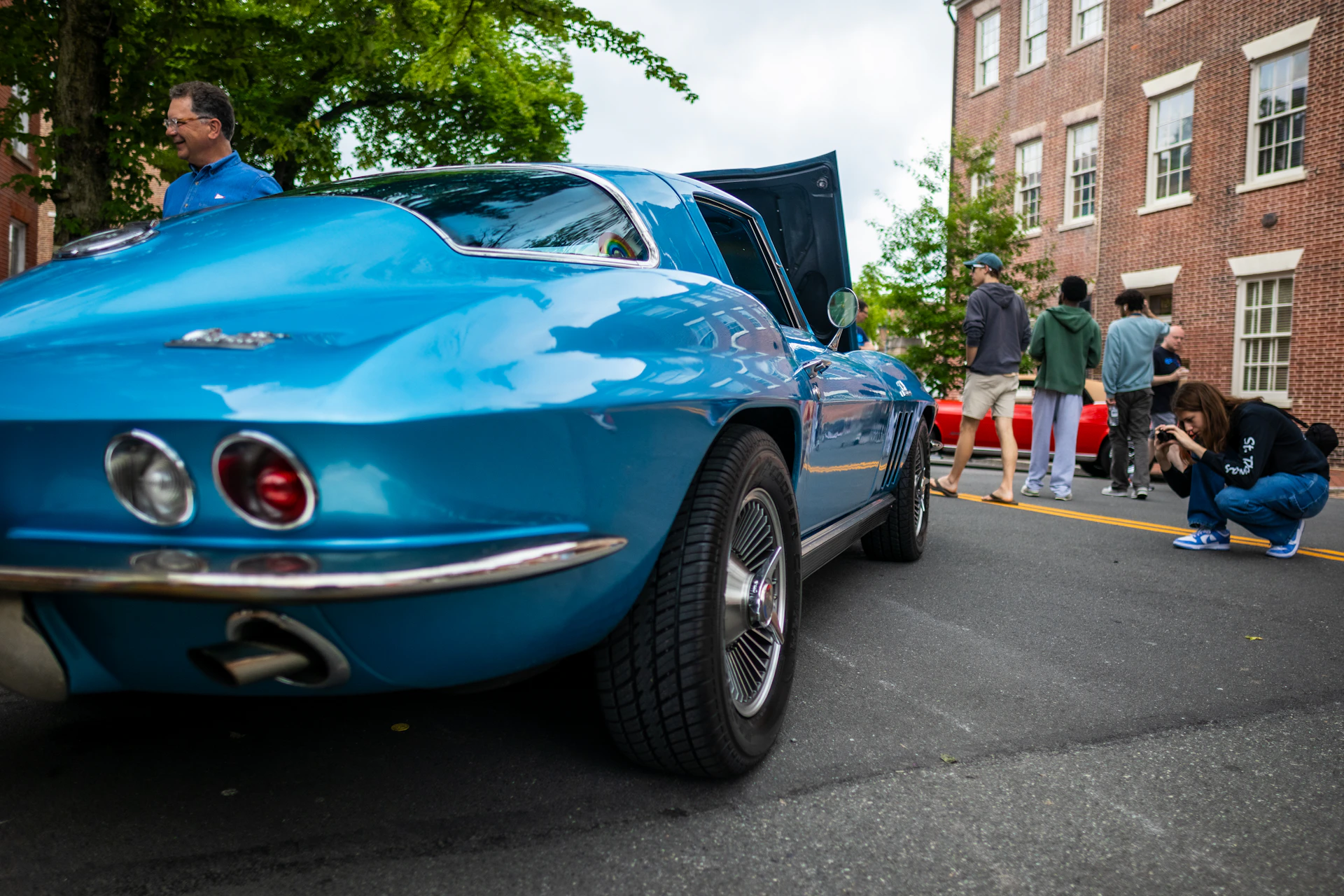 a man kneeling down next to a blue car