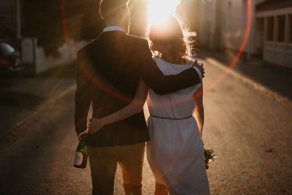 a bride and groom walking down the street at sunset