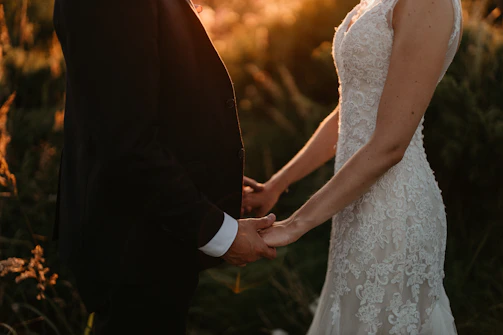 a bride and groom hold hands as the sun sets