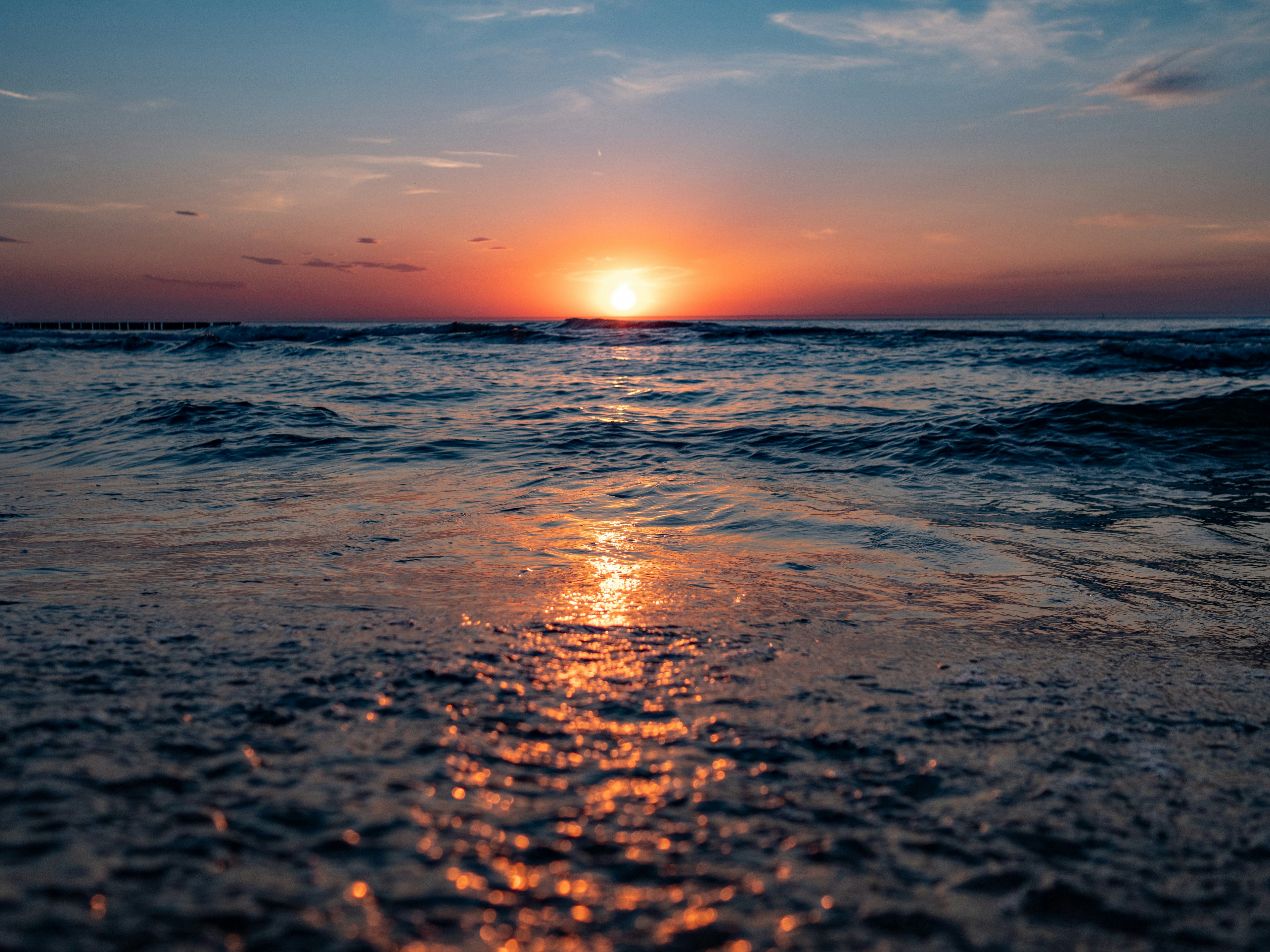 the sun is setting over the water at the beach