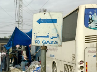 a white bus parked next to a blue and white sign
