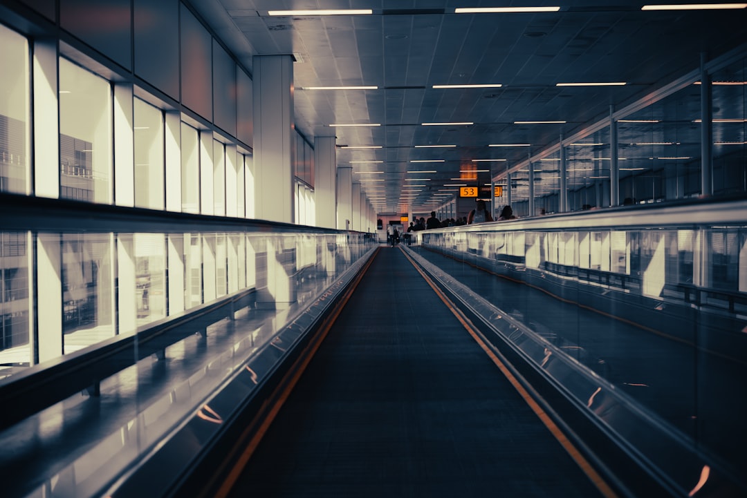 a train traveling through a train station next to tall windows,