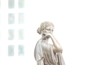 a statue of a woman holding her hand to her face