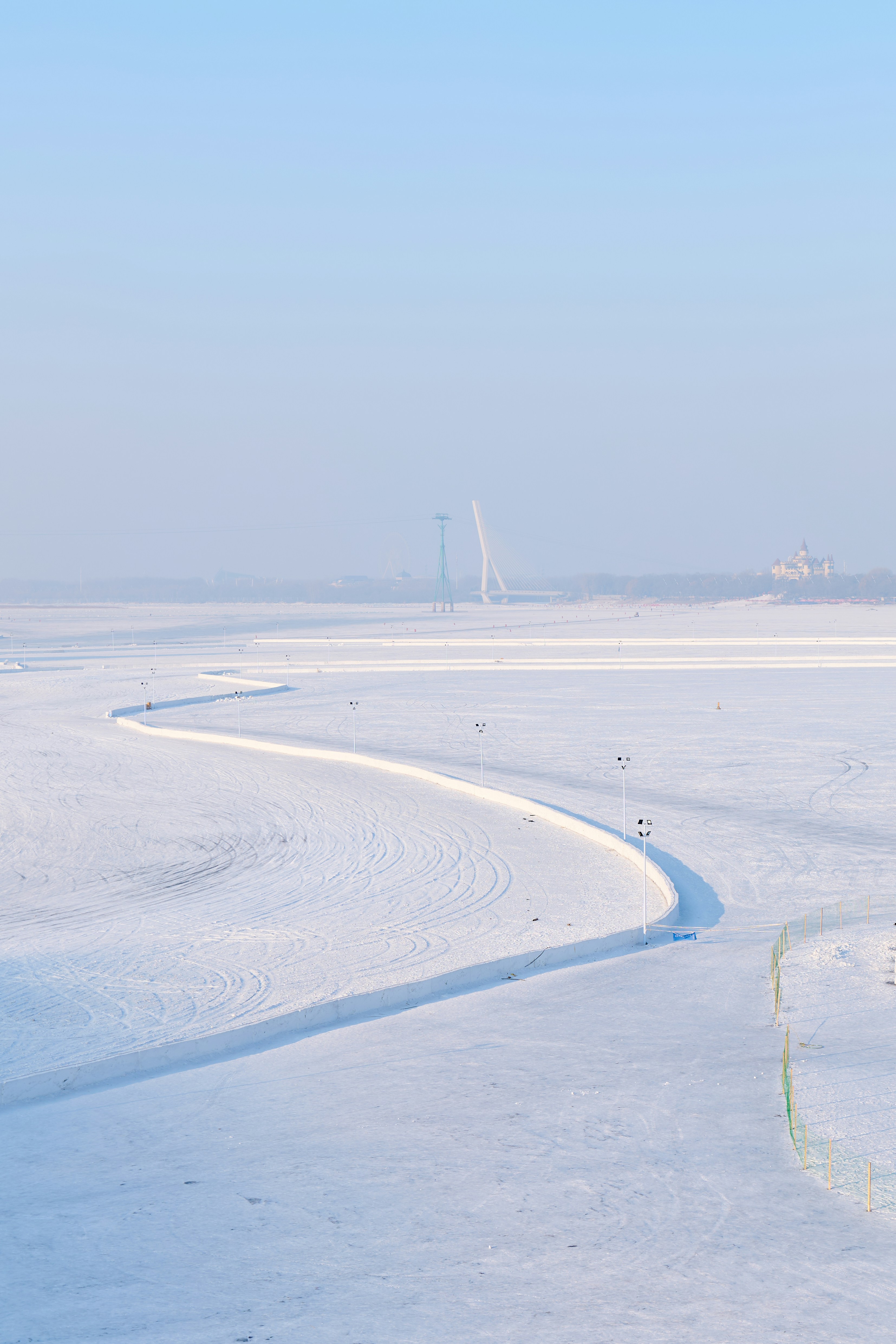 a snow covered field with a wind turbine in the distance