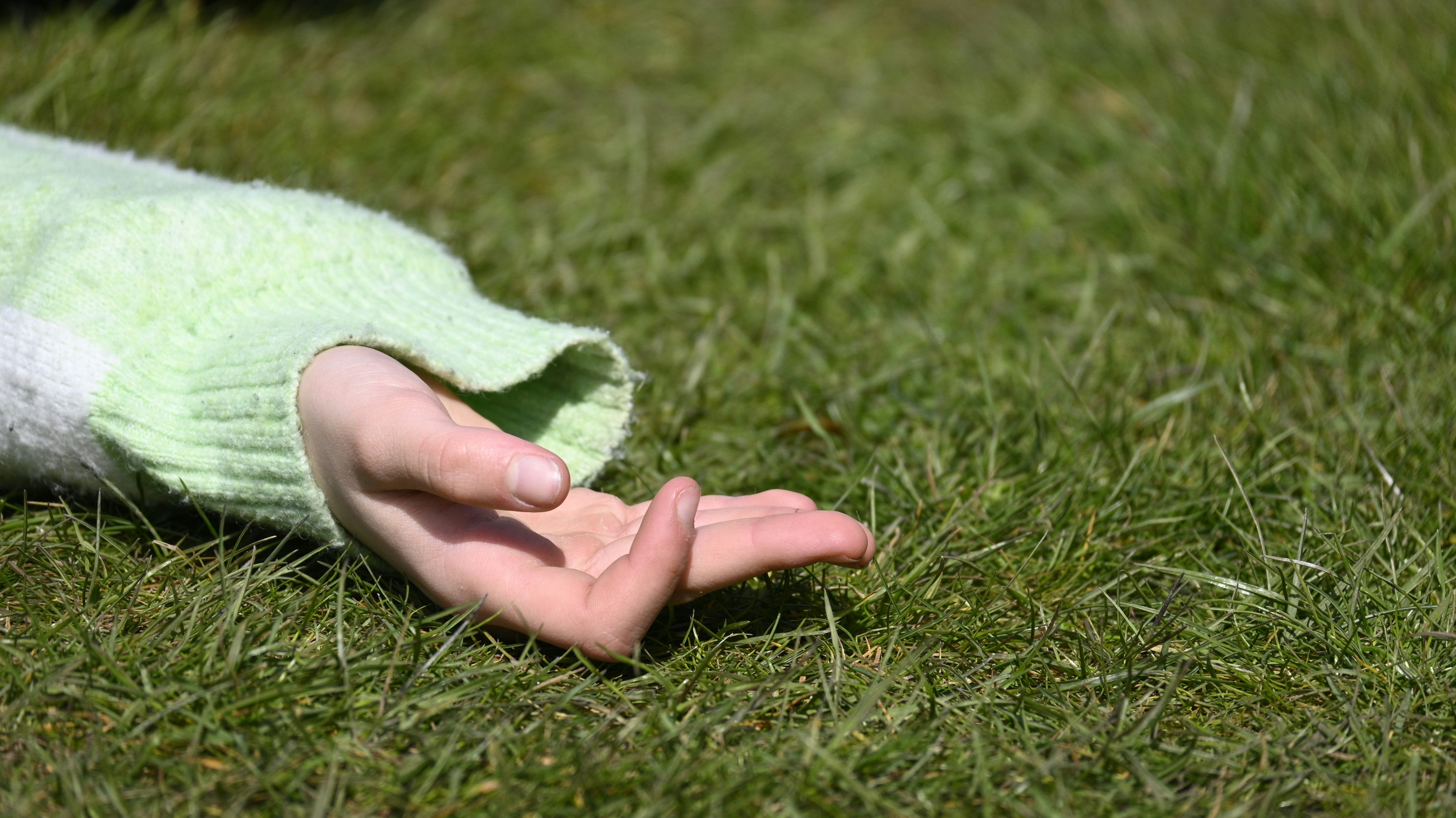 a person in a green sweater laying on the grass