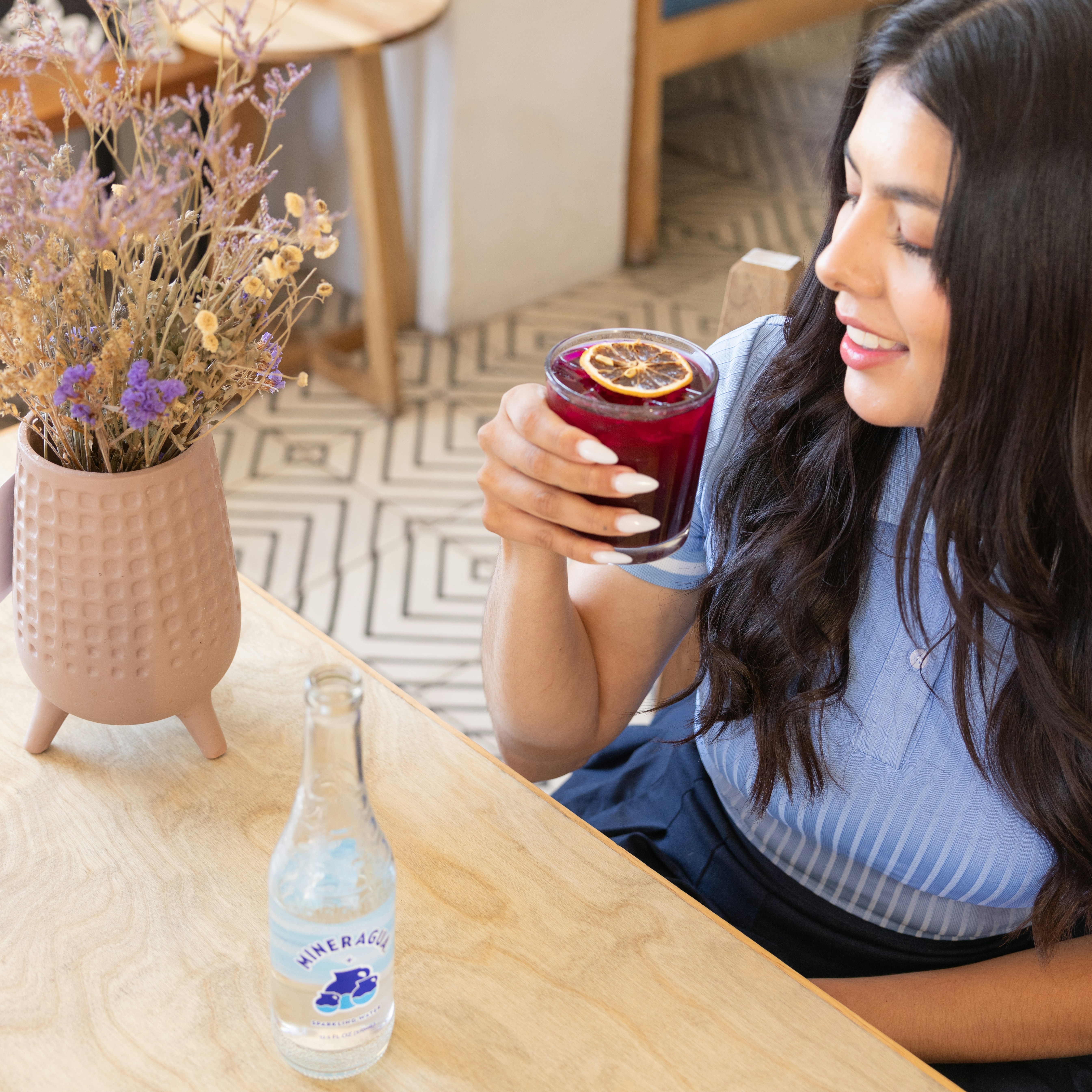 a woman sitting at a table holding a drink