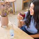 a woman sitting at a table holding a drink