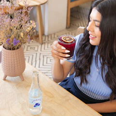 a woman sitting at a table holding a drink