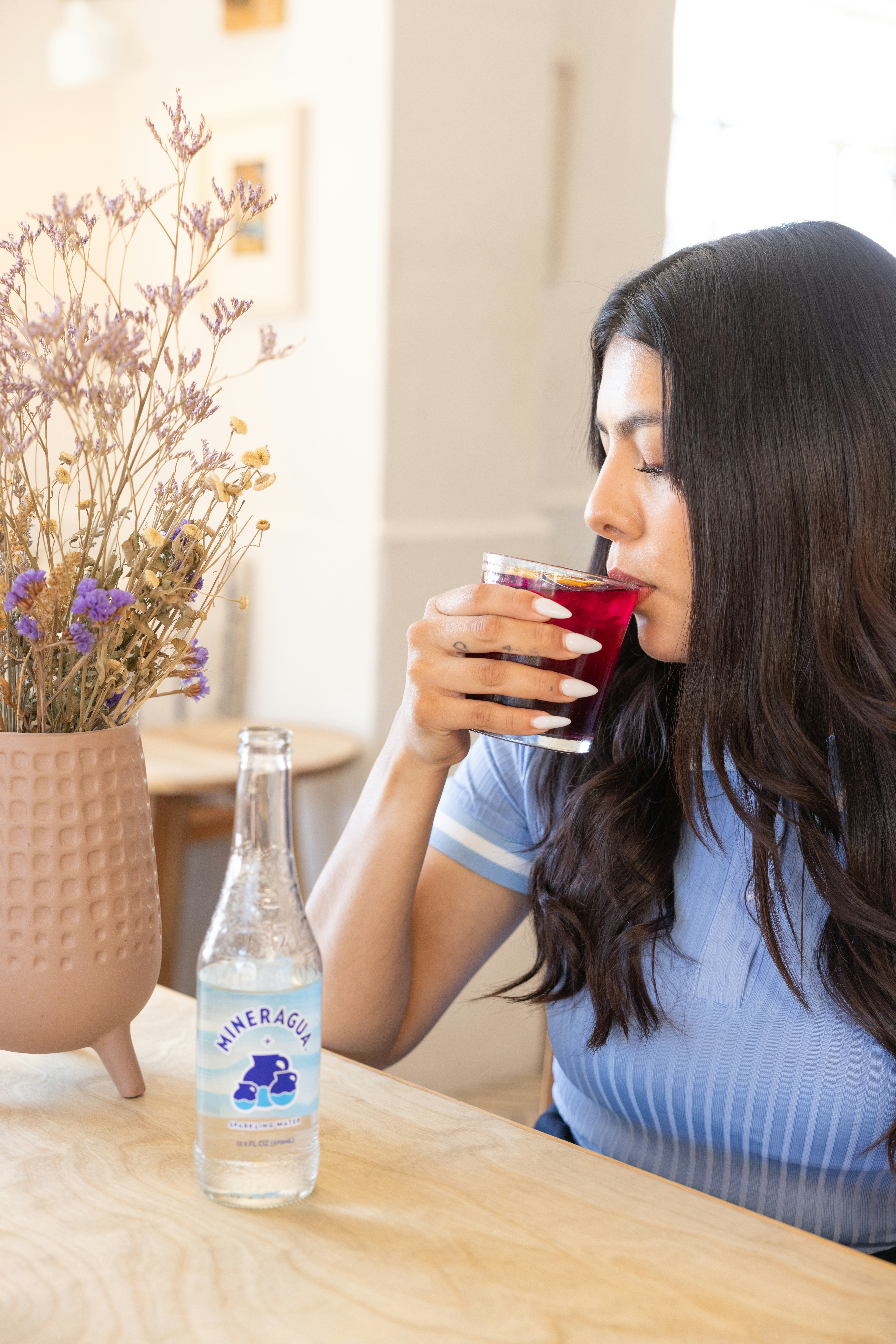 a woman sitting at a table drinking a glass of water