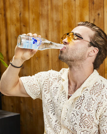 a man in a white shirt drinking a bottle of water