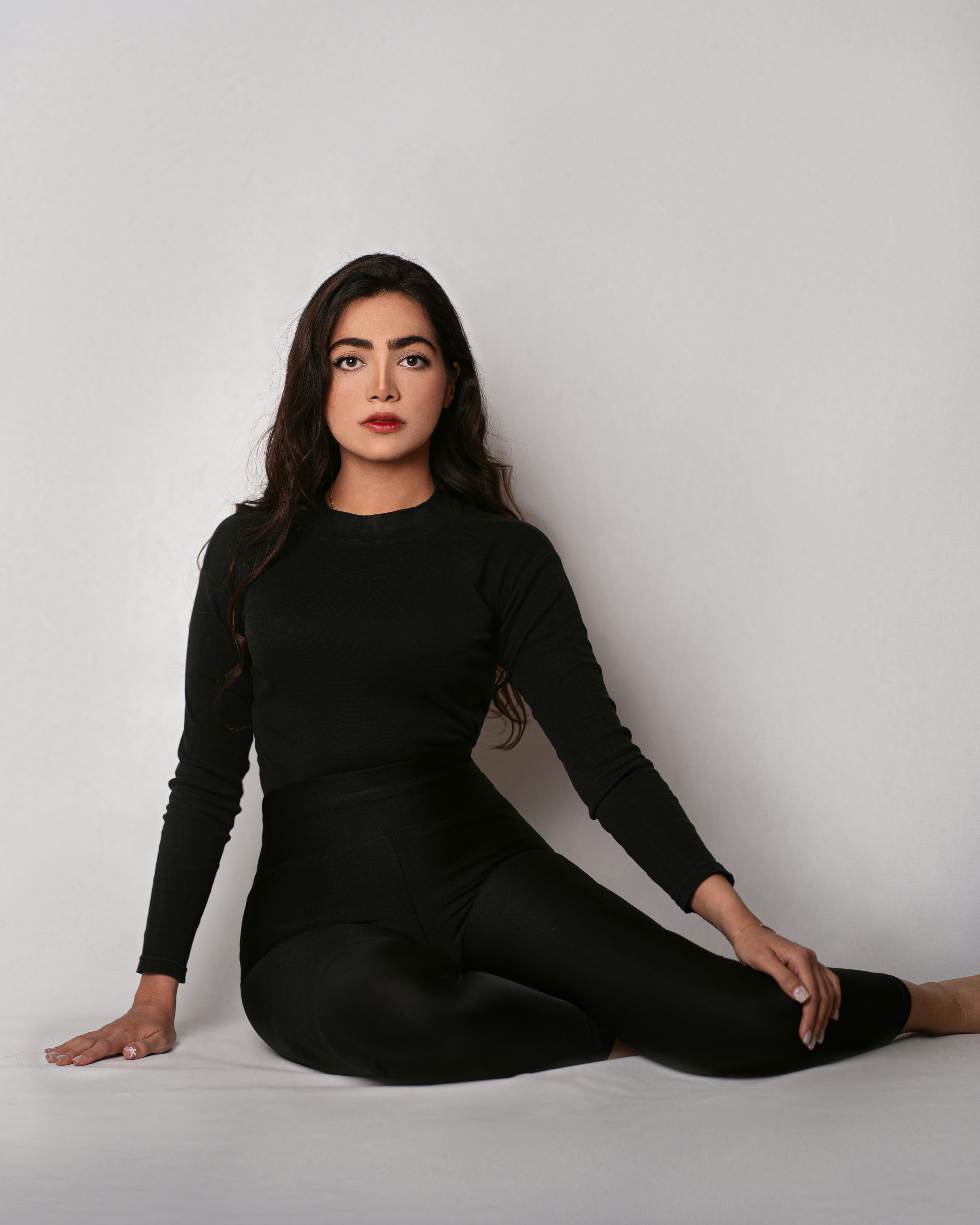 a woman sitting on the floor in a black dress