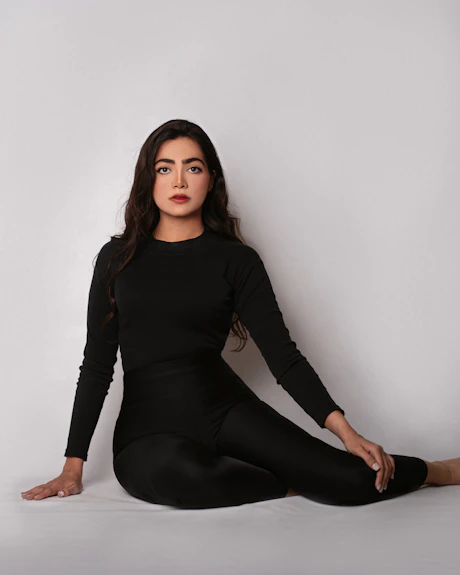 a woman sitting on the floor in a black dress