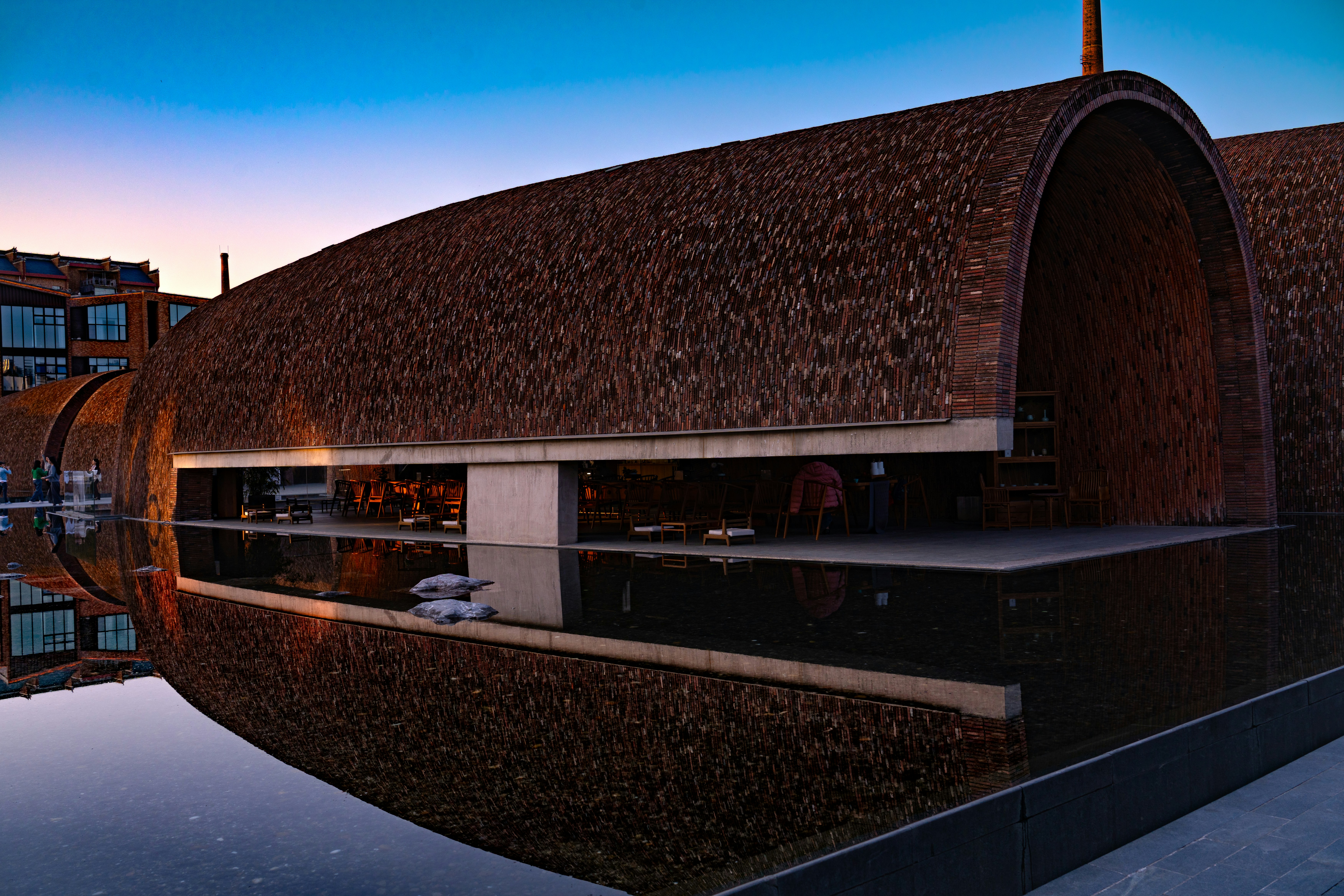 a building with a thatched roof next to a body of water