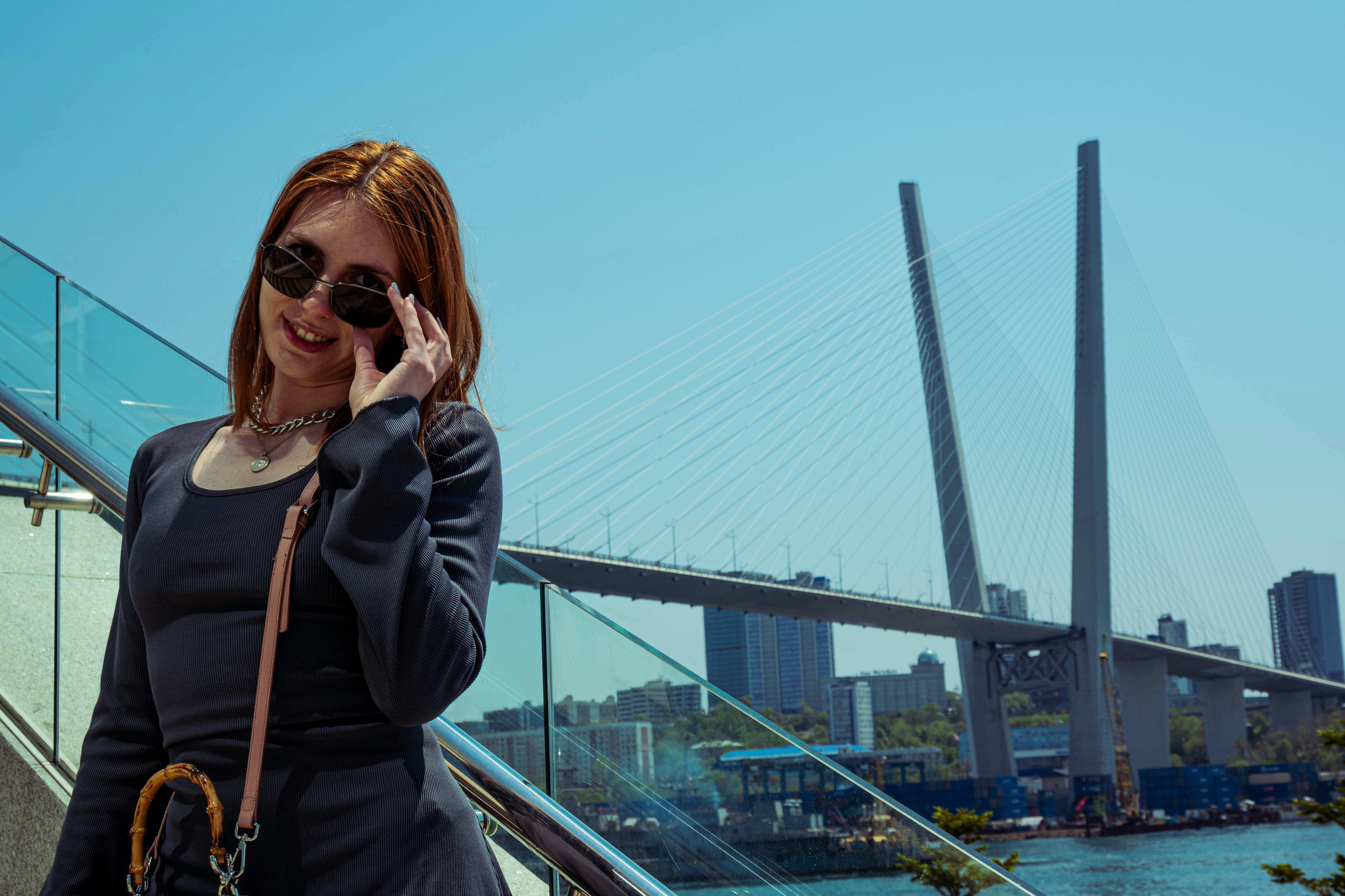 橋の上に立って携帯電話で話す女性