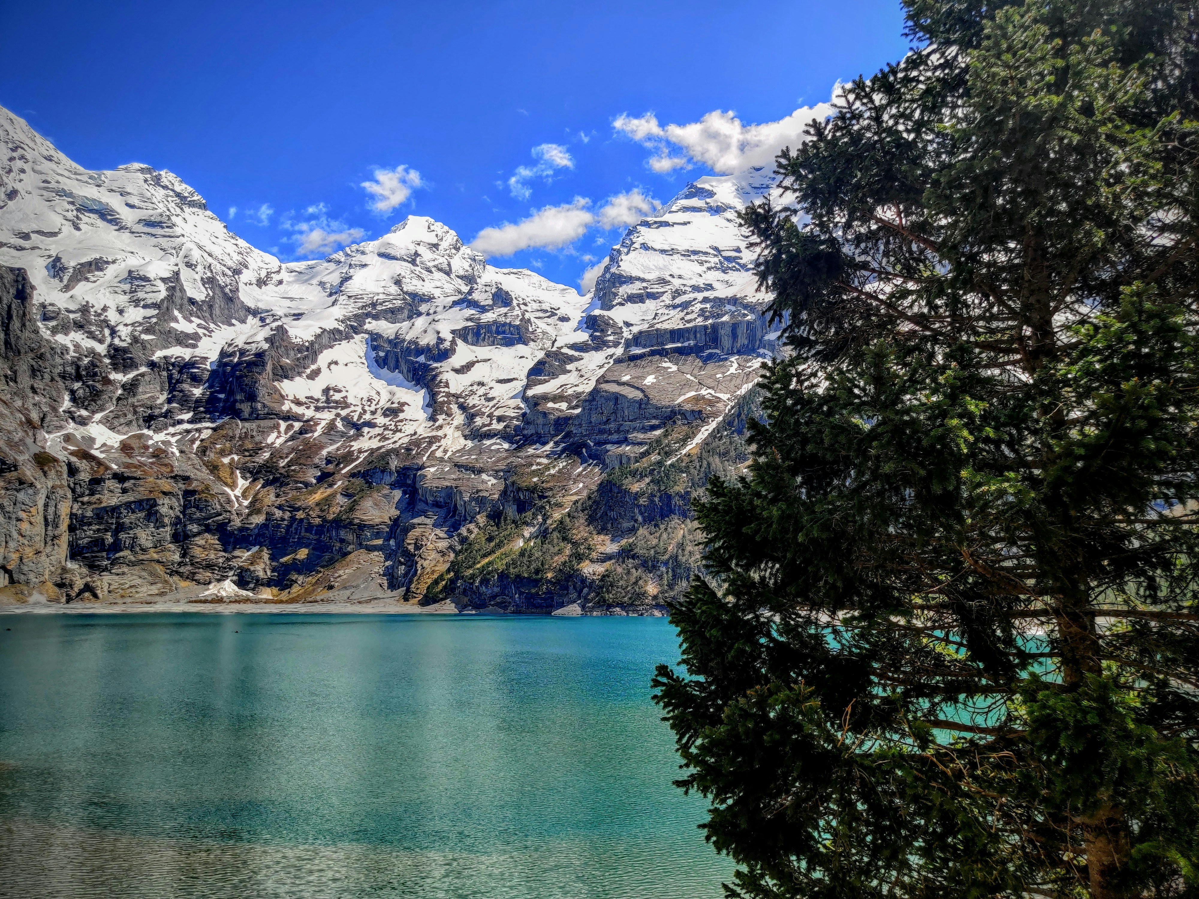 a lake surrounded by snow covered mountains under a blue sky