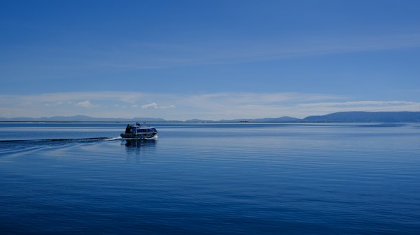 A small boat traveling across a large body of water — Lake Titicaca, Peru