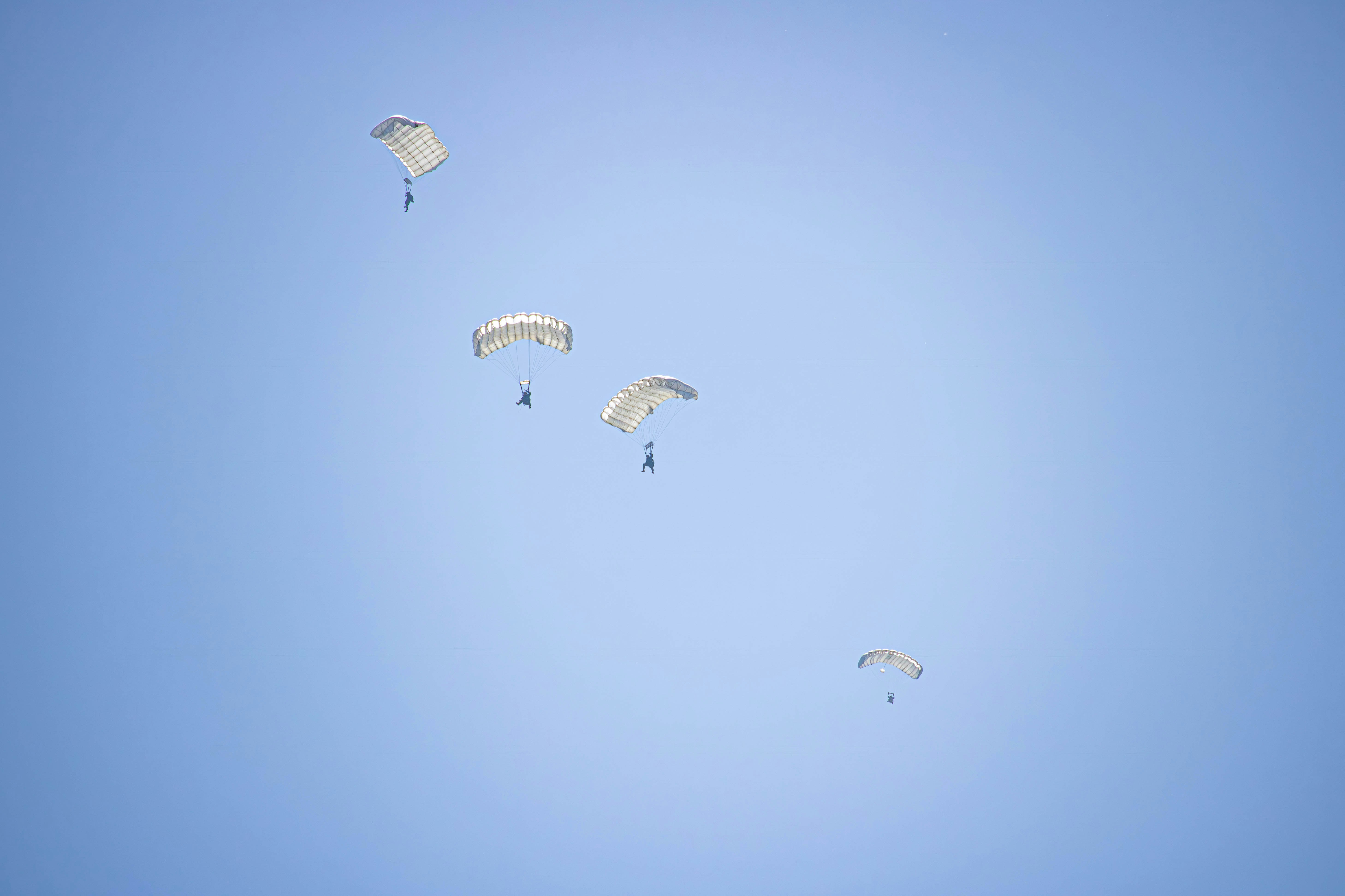 a group of parasailers flying through a blue sky