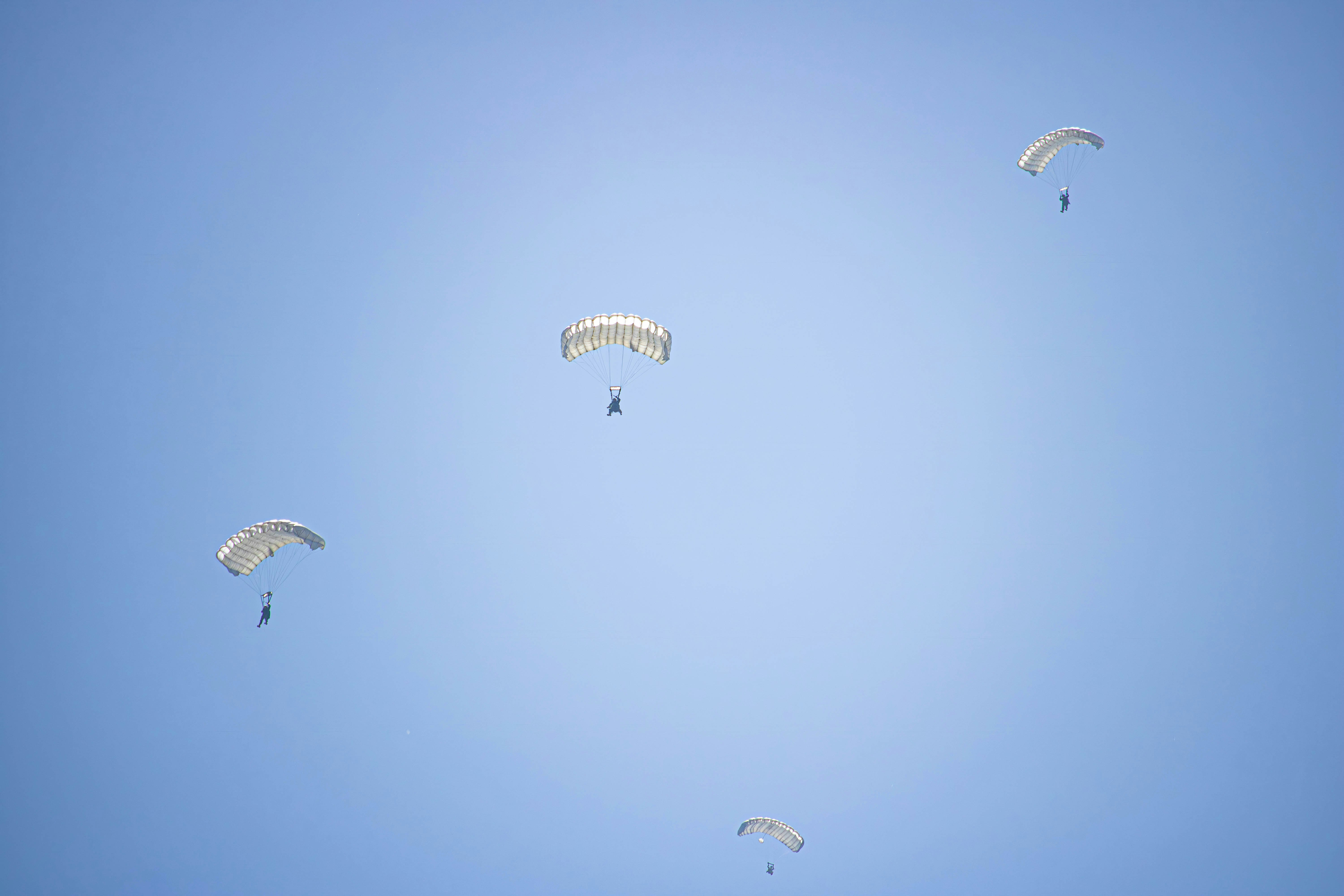 a group of parasailers flying through a blue sky