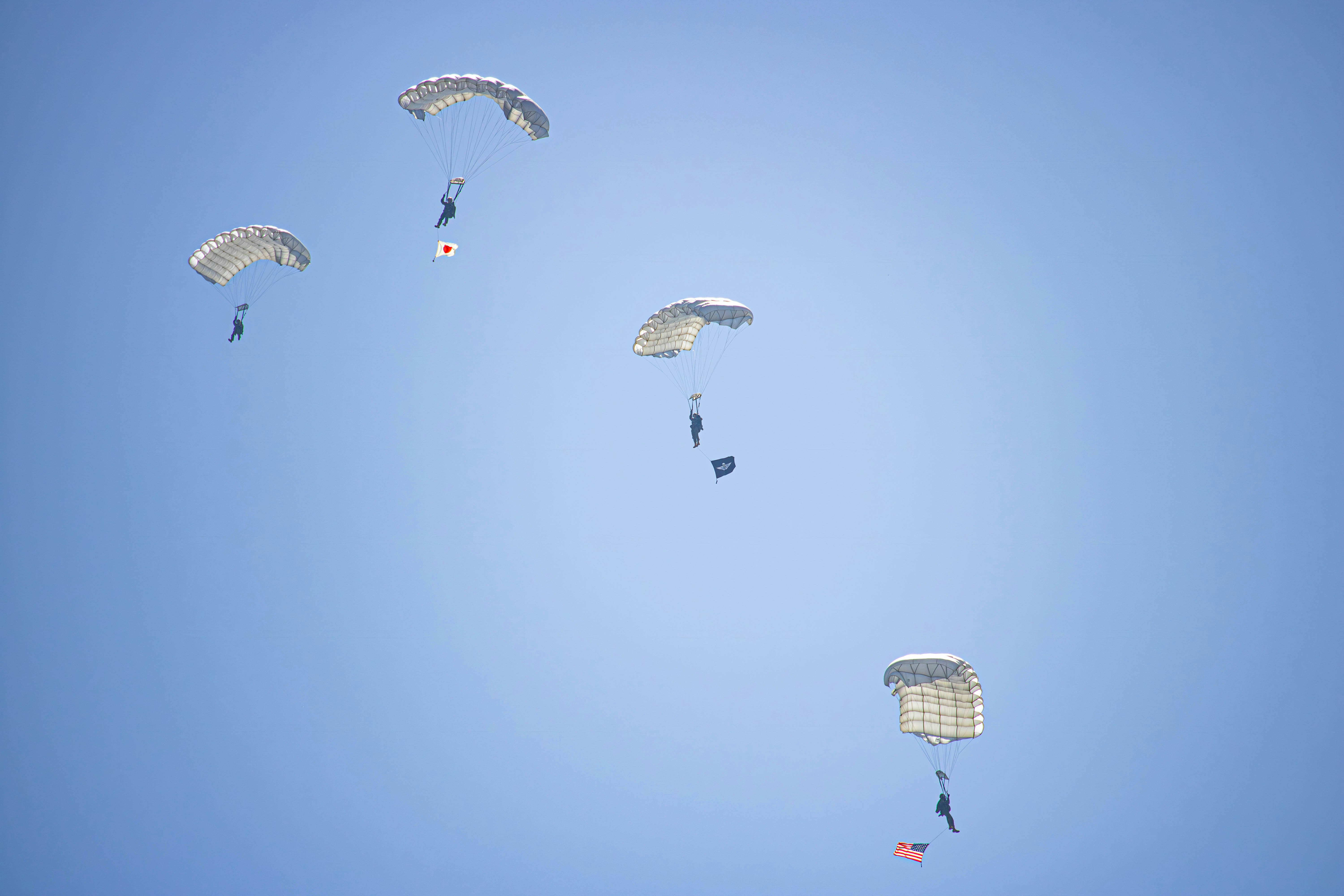 a group of parachutes flying through a blue sky