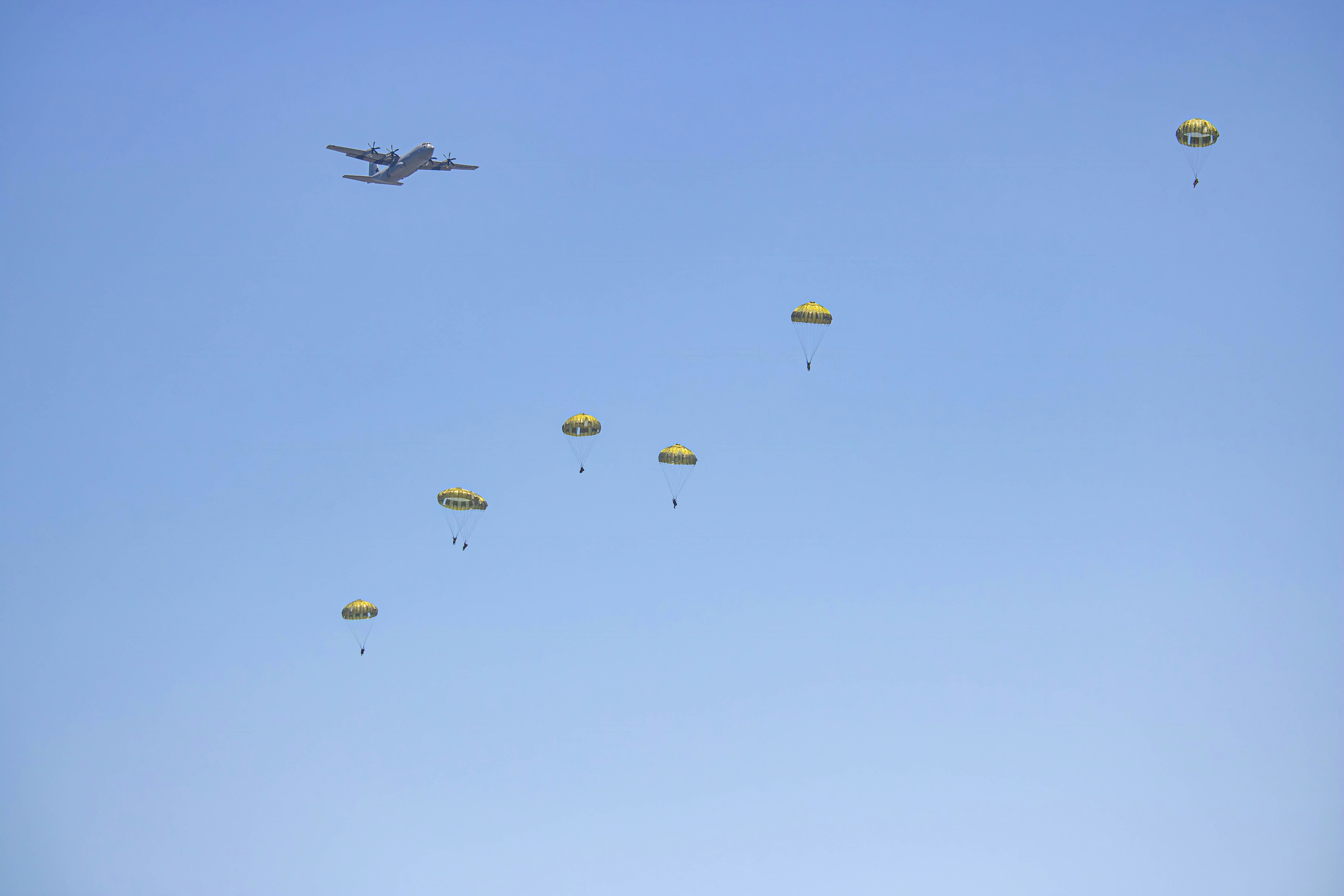 a group of yellow parachutes flying through a blue sky