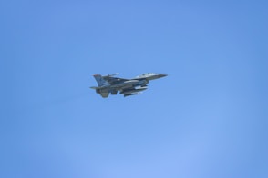 a fighter jet flying through a blue sky