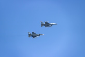 two fighter jets flying through a blue sky