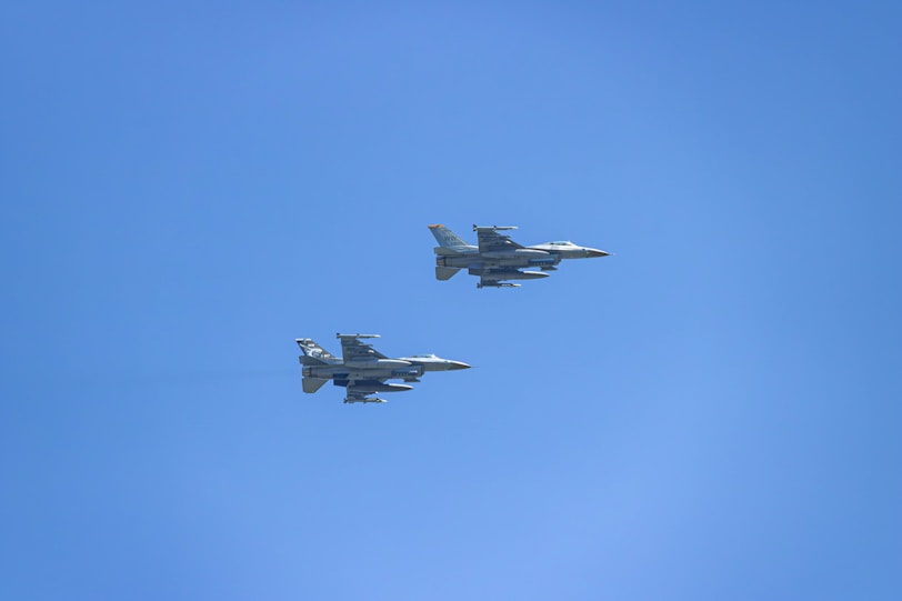 two fighter jets flying through a blue sky
