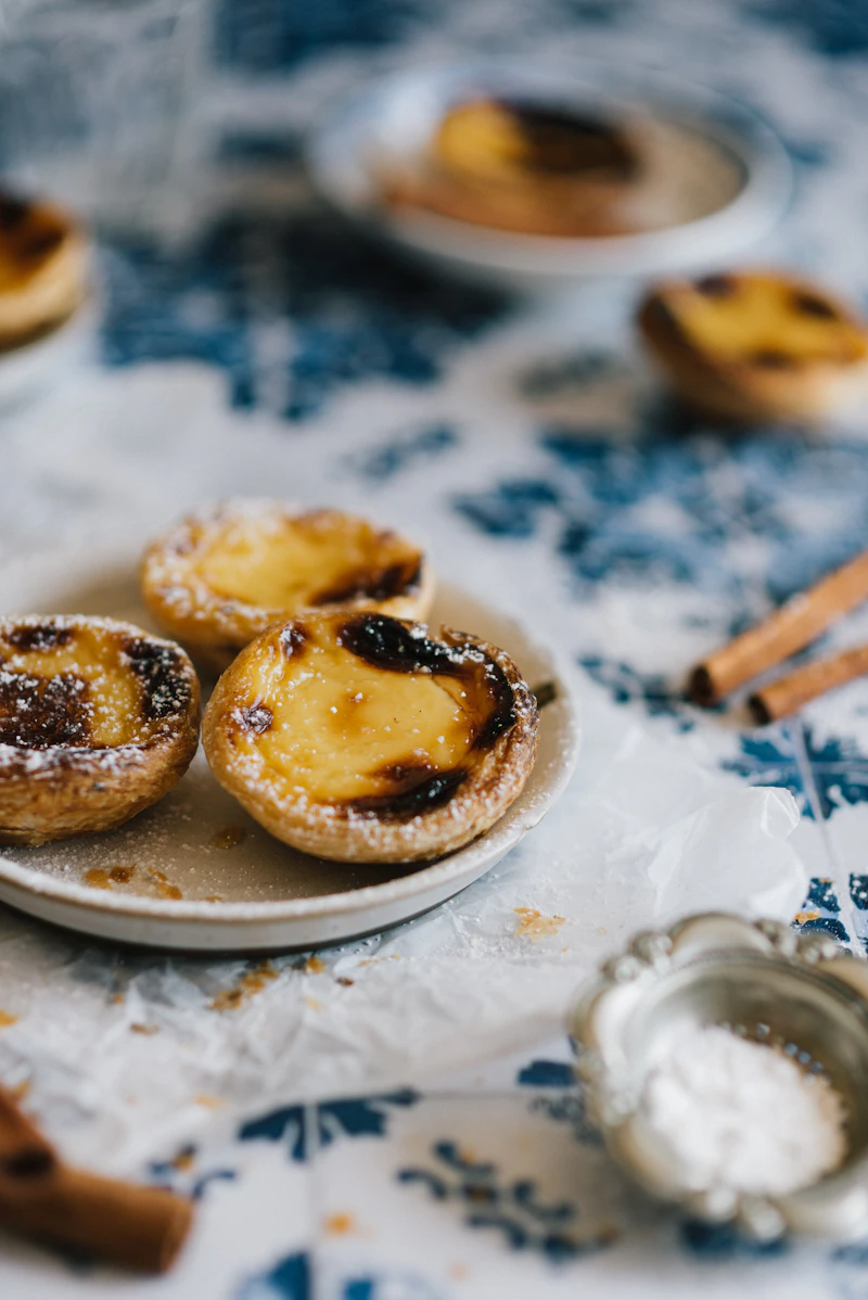 Portugiesische Pastéis de Nata auf einem Teller — Nahaufnahme mit Puderzucker