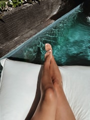 a woman laying on top of a white pillow next to a pool