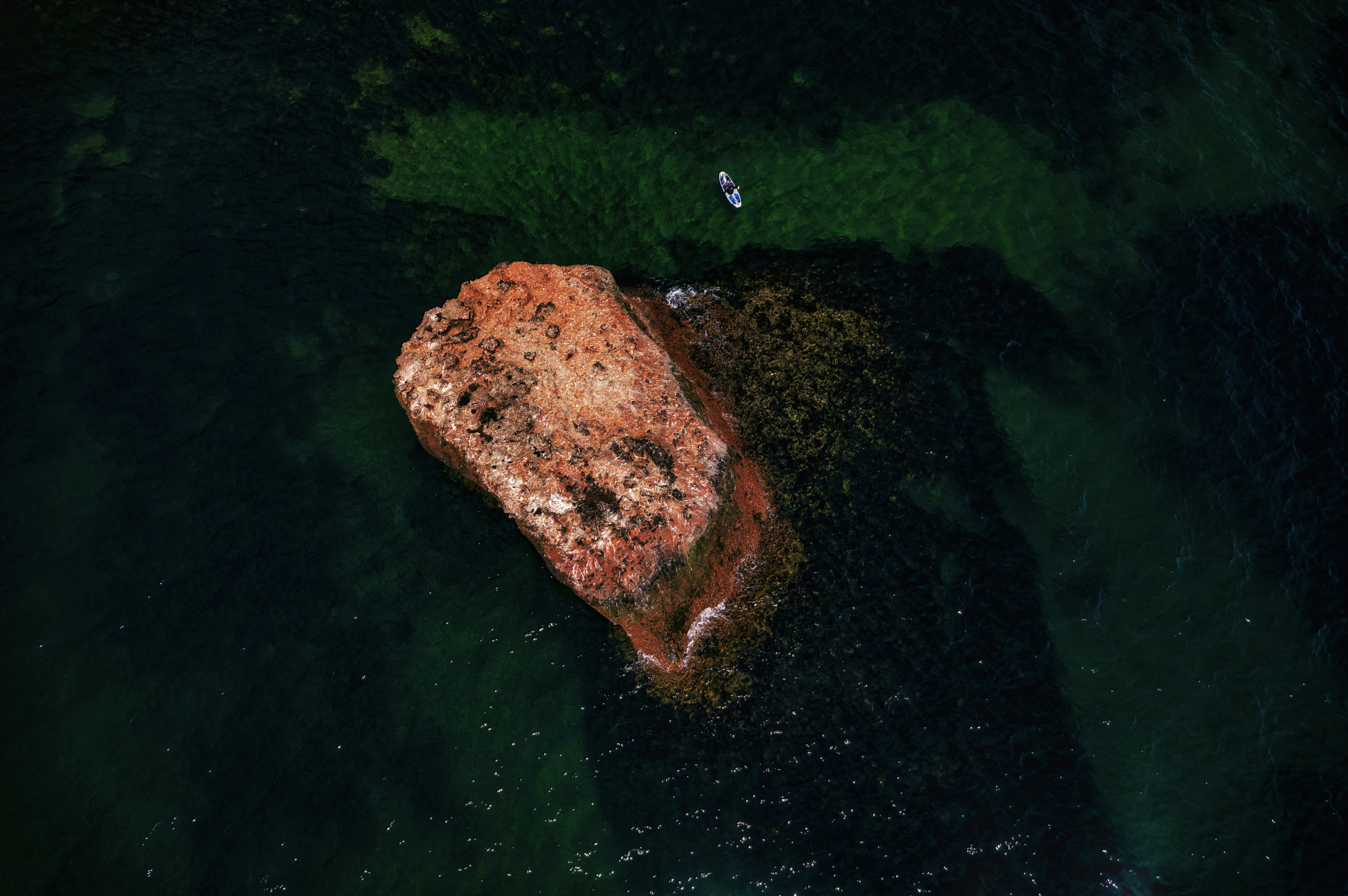 an aerial view of a rock in the water