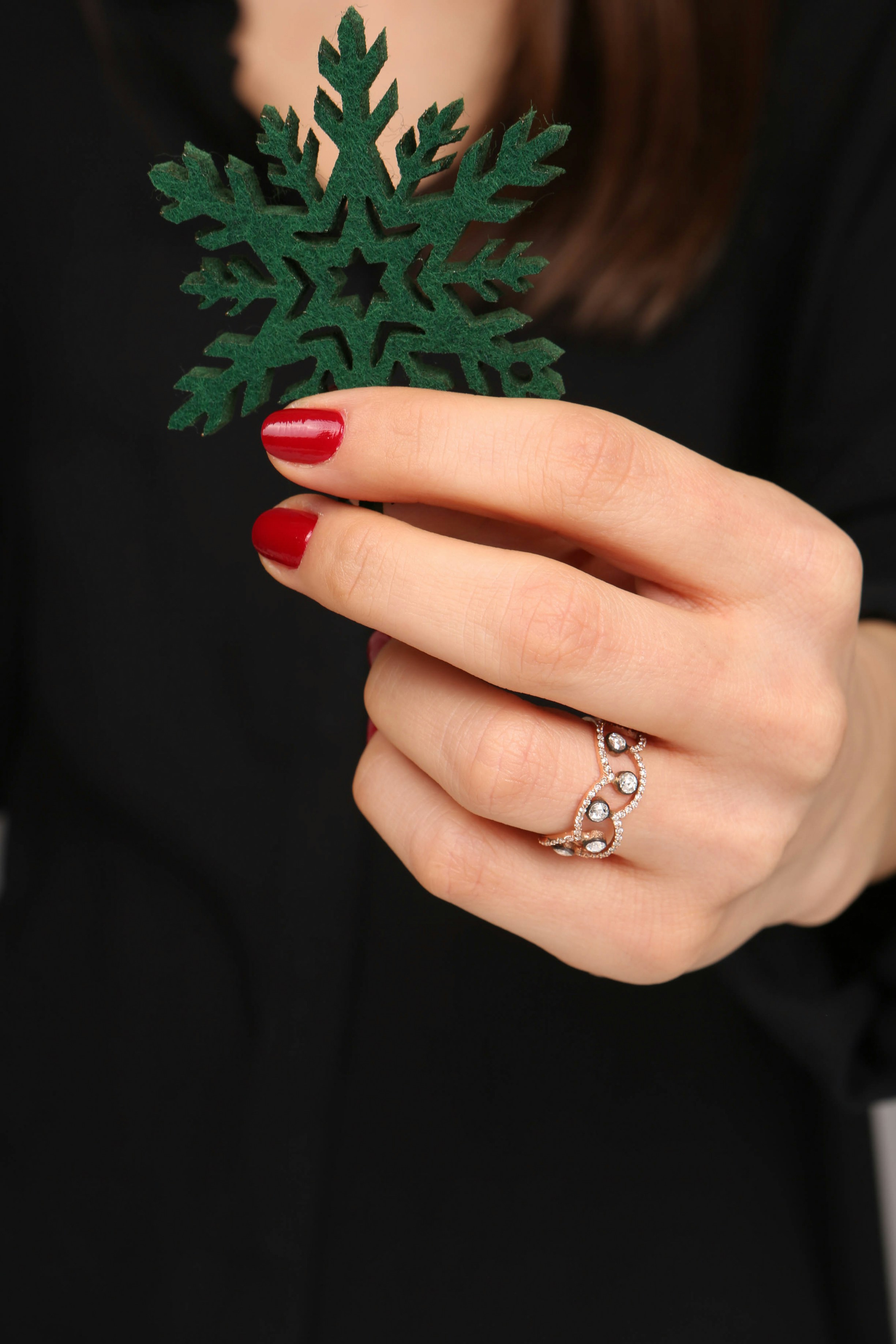 a woman's hand holding a green snowflake ornament