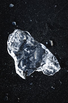 a piece of ice sitting on top of a black surface