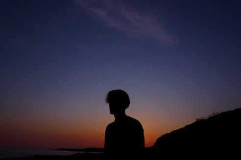 a silhouette of a person standing in front of a sunset