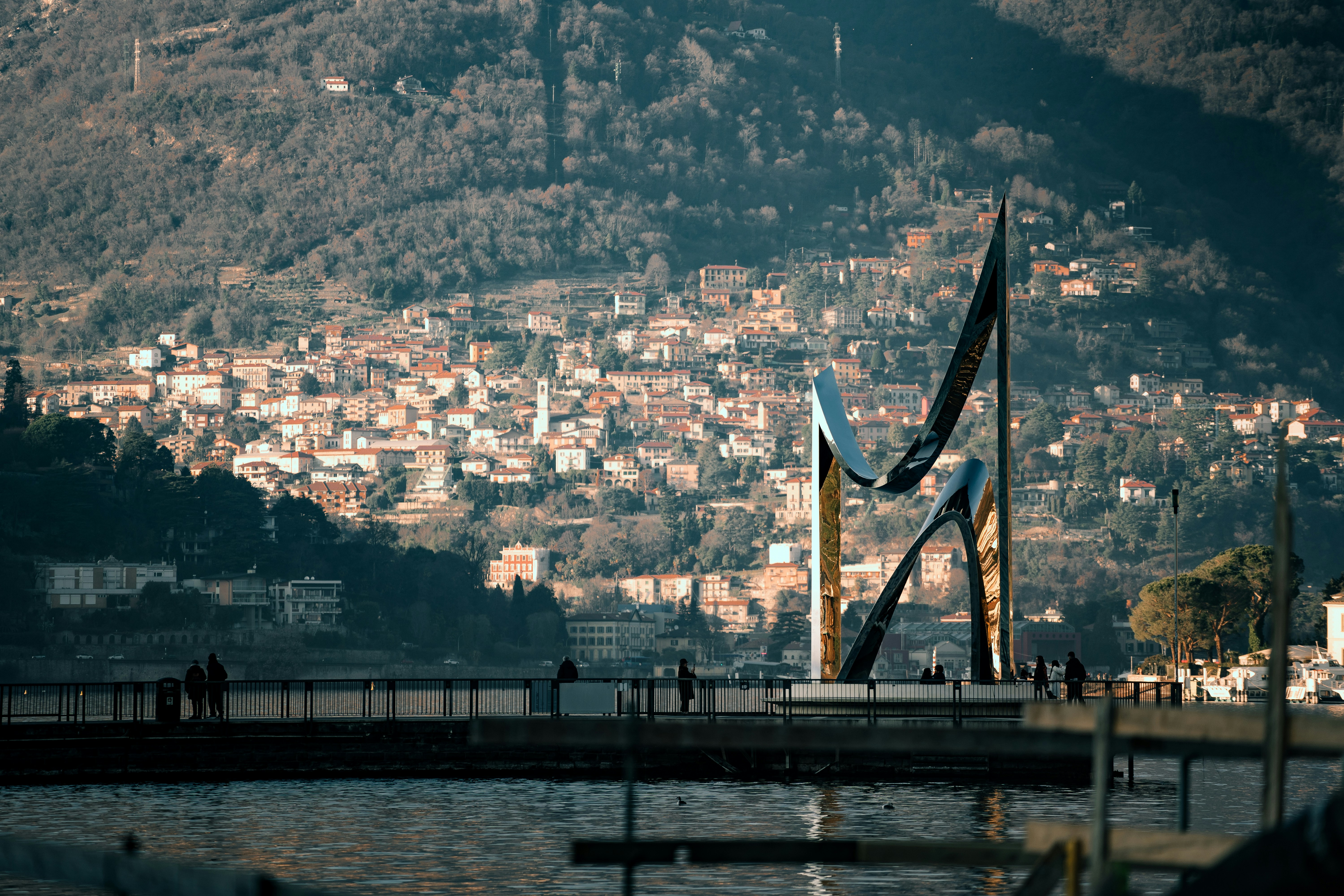 una statua di due persone in piedi su un molo accanto a uno specchio d'acqua