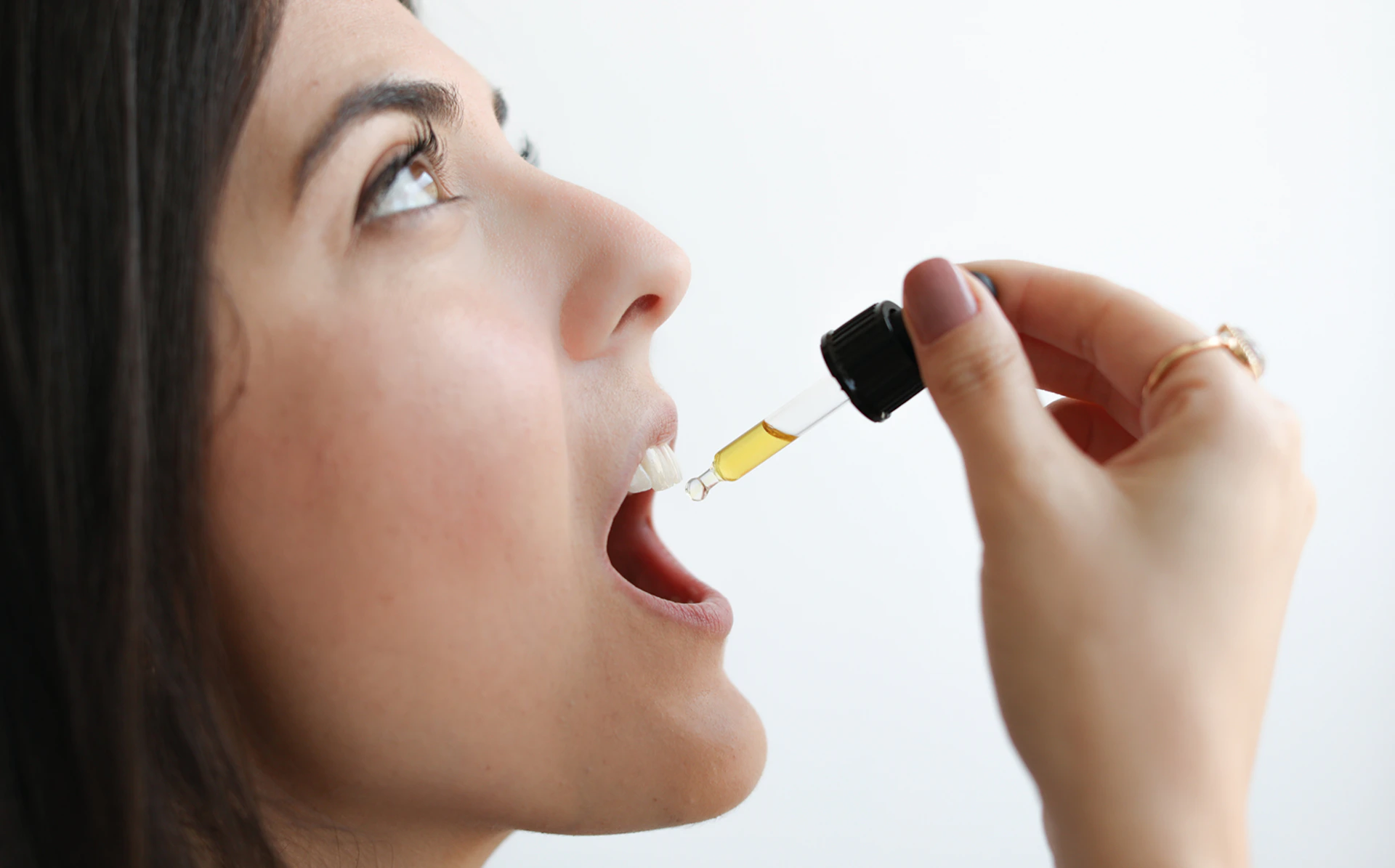 Woman taking drops from a dropper into her mouth