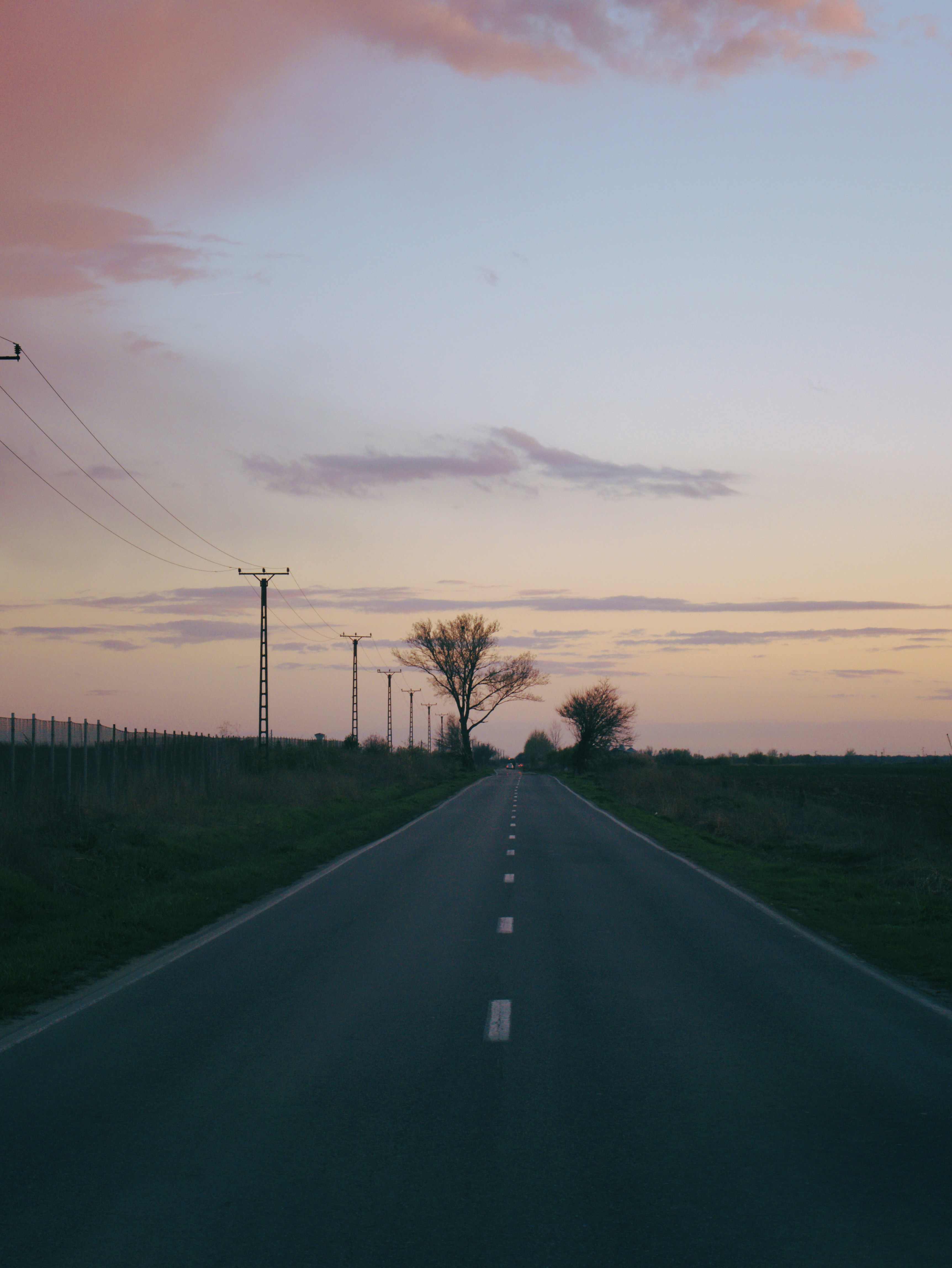 a long empty road with power lines in the distance