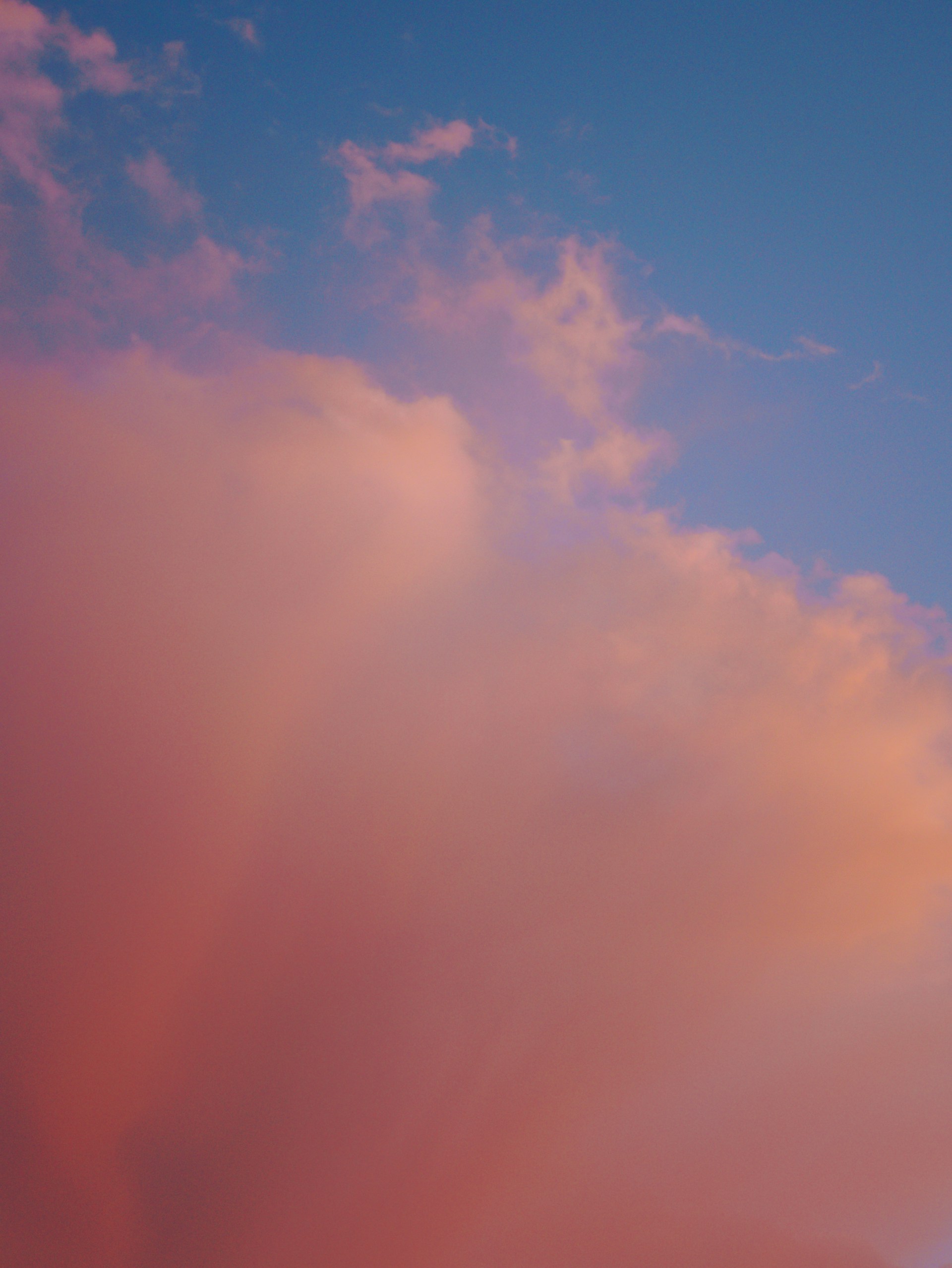 a plane flying through a pink cloud filled sky