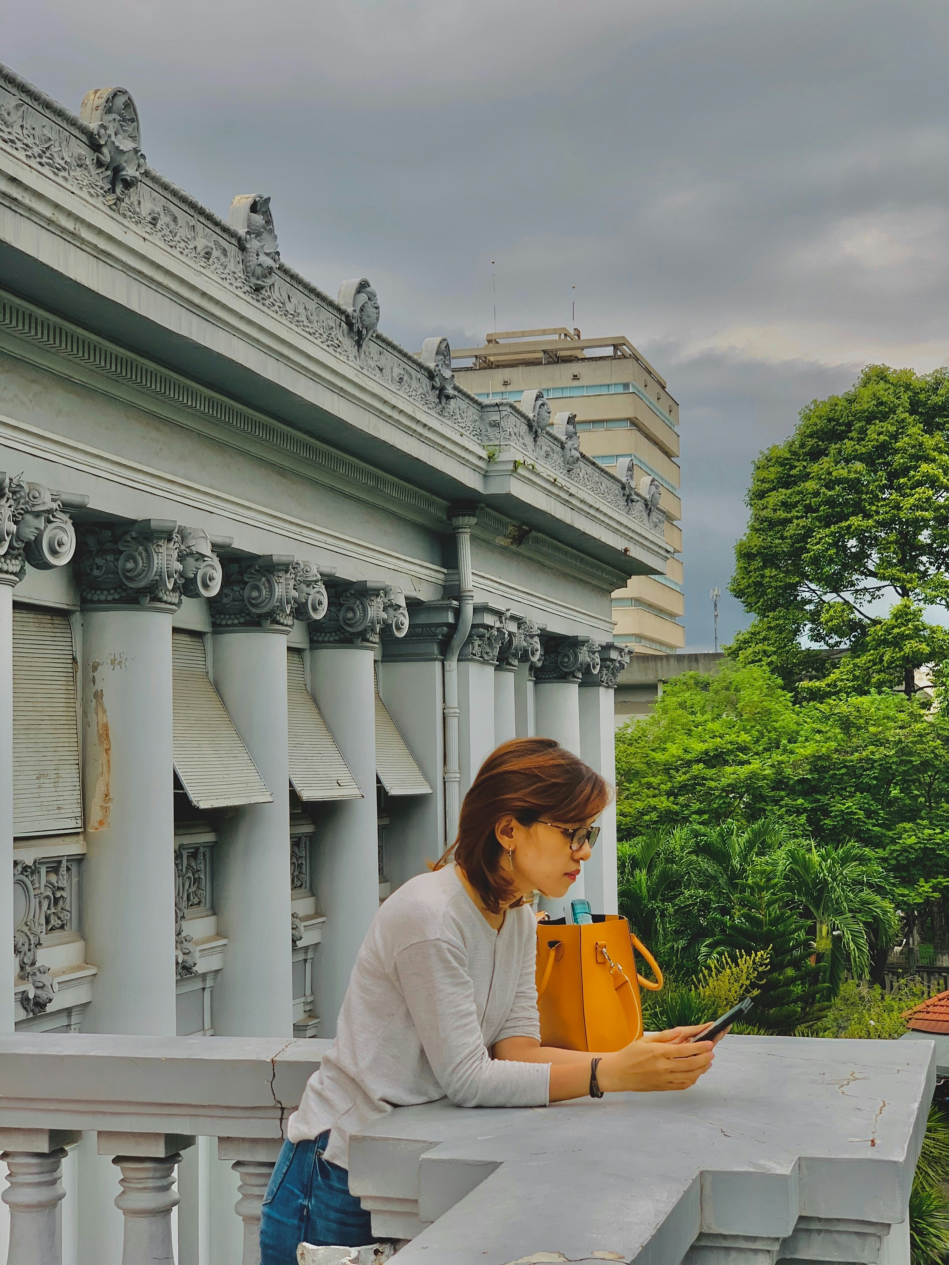 A woman sitting on a ledge looking at her cell phone