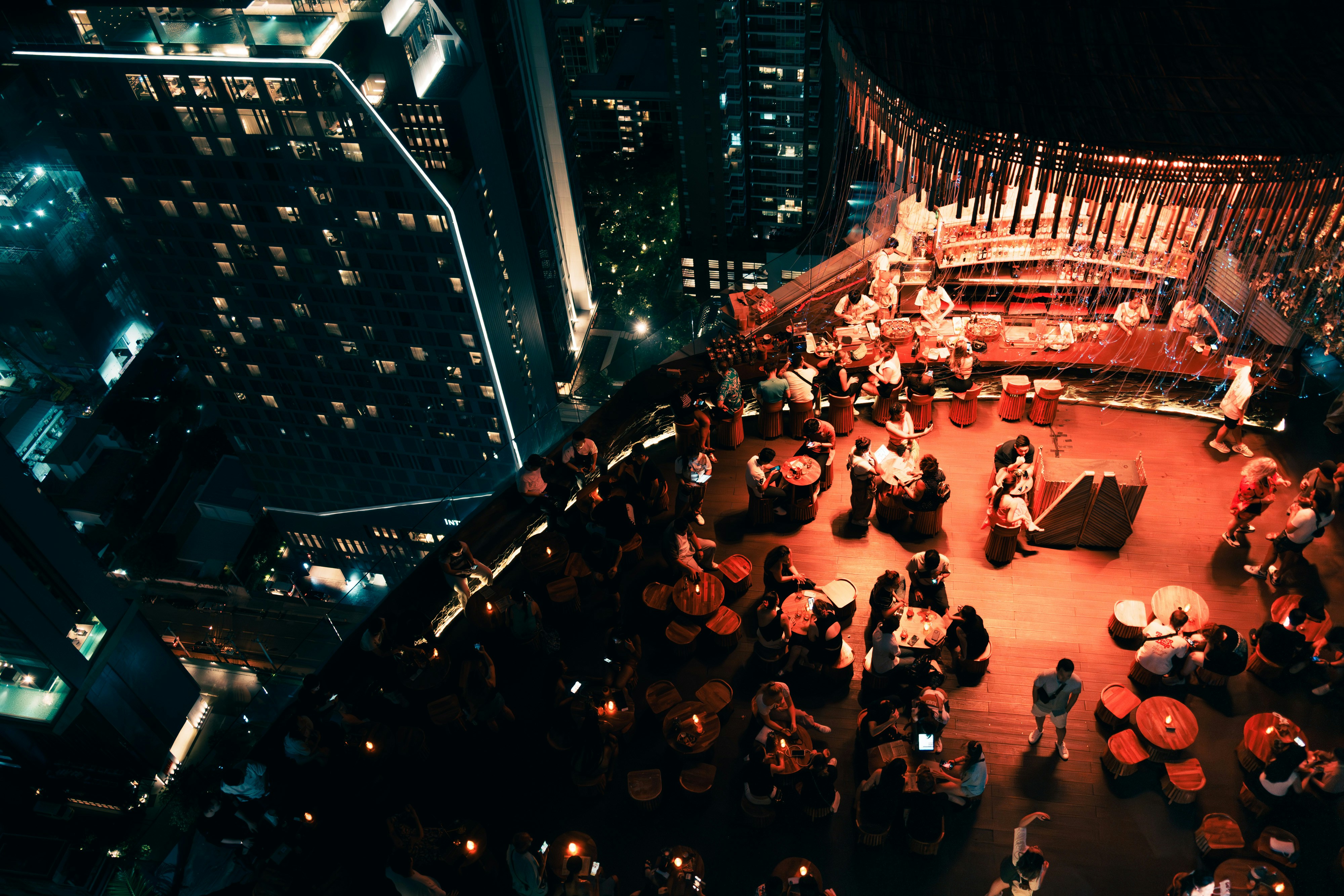 Groups around lamplit tables in a rooftop bar at night