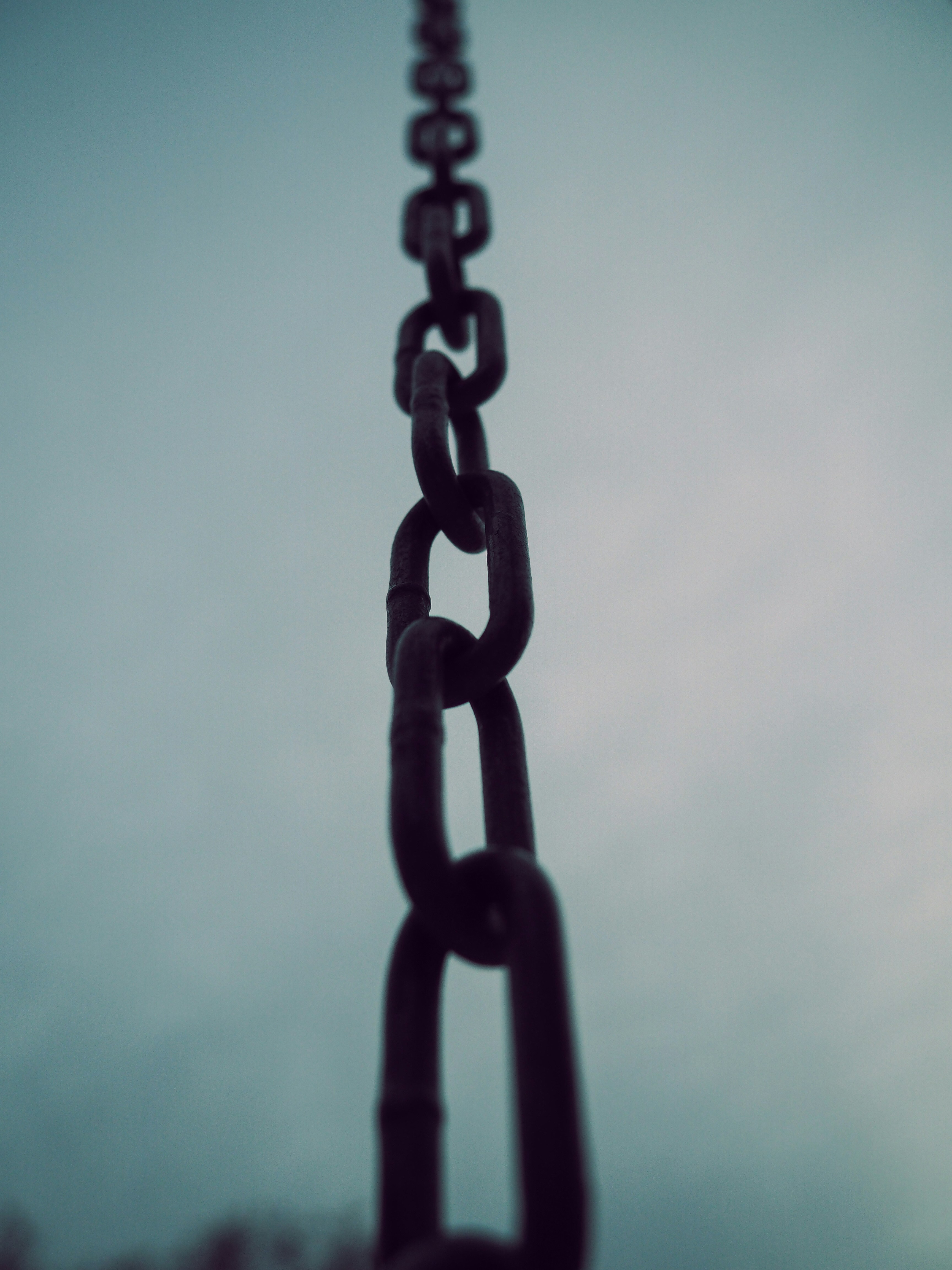 A black chain snaking up into a dark sky.