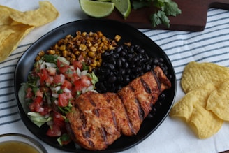 a plate of chicken, black beans, corn, and salsa