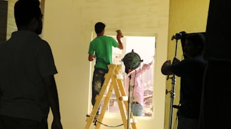 a man standing on a stepladder in front of a camera