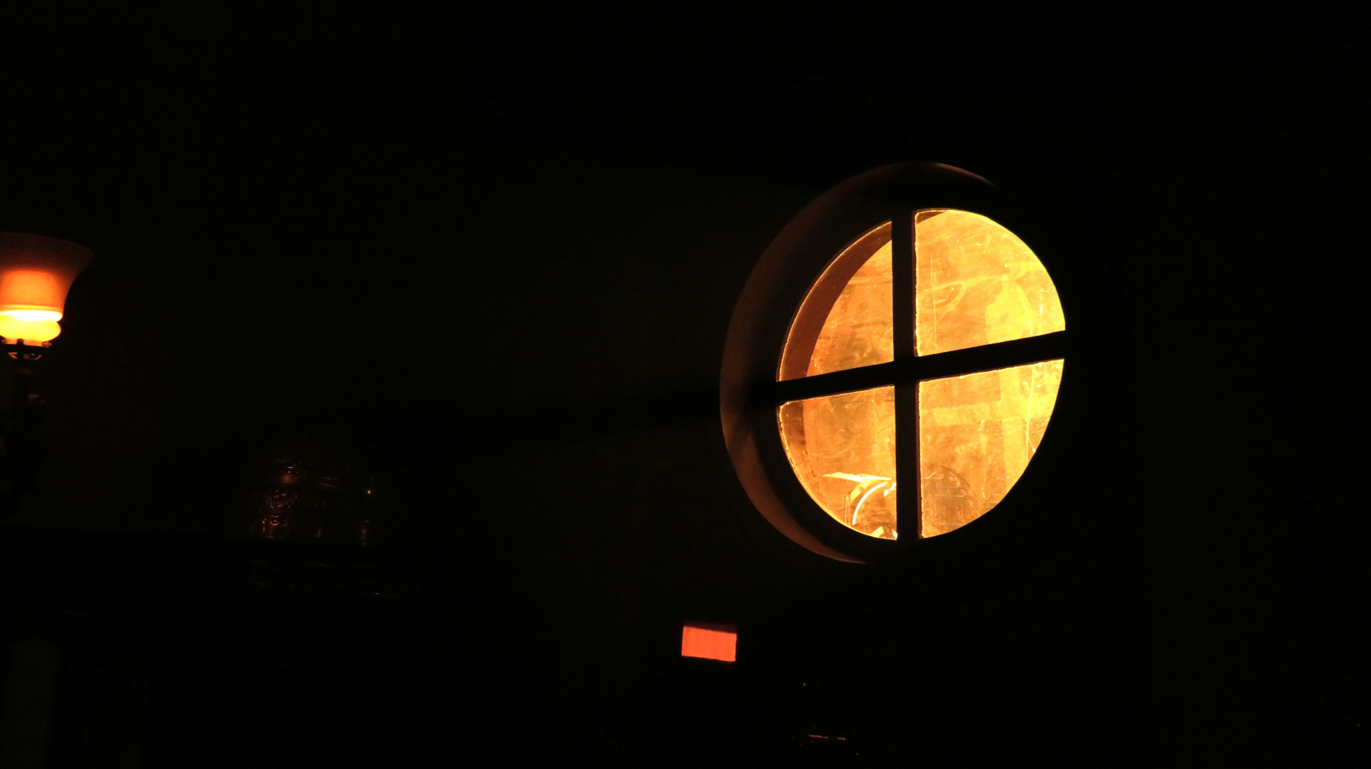 a dark room with a round window and a lamp